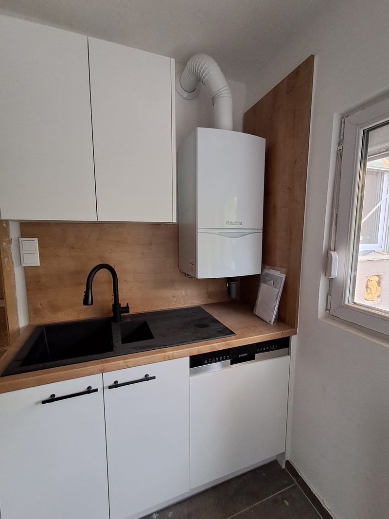 Neu installierte Vaillant-Gastherme über der Küchenzeile in einer Wiener Wohnung, fachgerecht an Abluft und Warmwasser angeschlossen