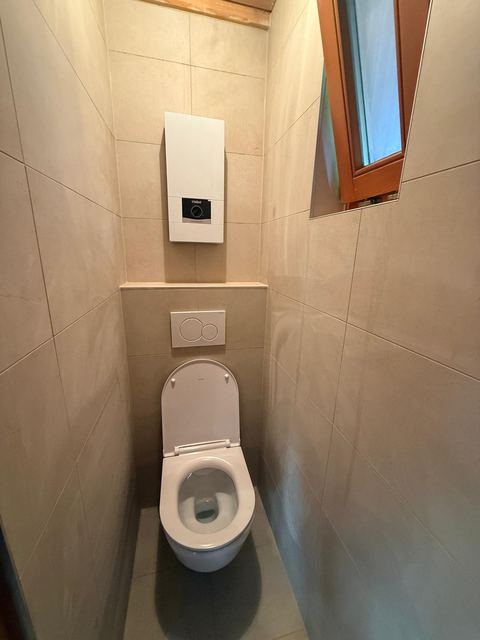 Elektro-Durchlauferhitzer, platzsparend über einem wandhängenden WC in einem kleinen Gäste-WC montiert