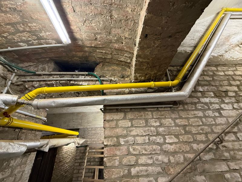 Sanierte und gedämmte Gas- und Wasser-Steigleitungen im Kellergang eines Wiener Zinshauses